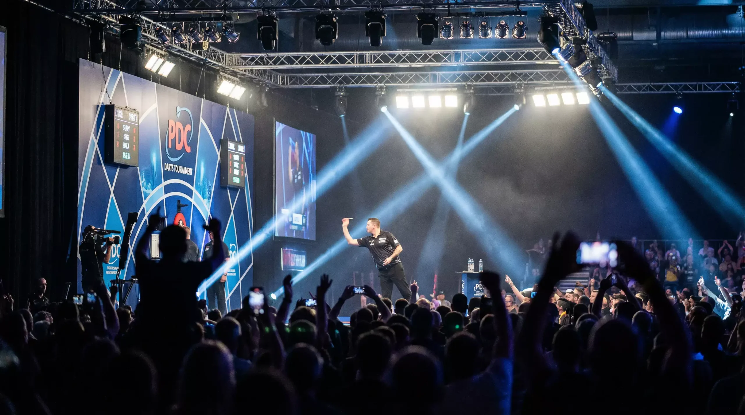 Darts-Bühne mit Spieler am Oche unter Scheinwerferlicht – Live-Wetten auf Darts in Echtzeit