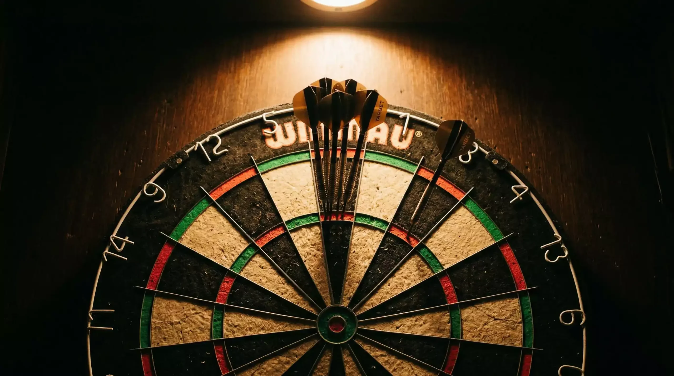 Dartpfeile neben einem Geschenkpaket mit Schleife auf einem Tisch – Darts-Wettbonus und Freiwetten