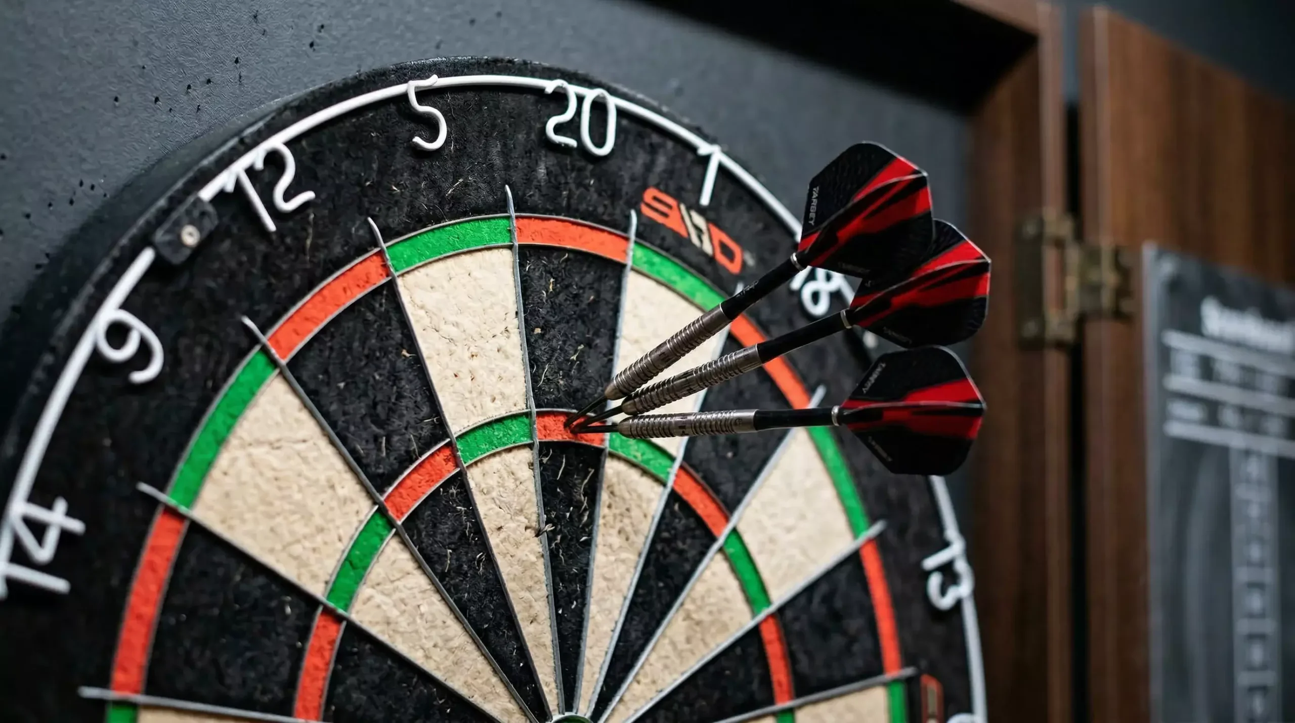 Drei Dartpfeile stecken dicht gruppiert im 20er-Segment einer Dartscheibe – Three-Dart-Average erklärt